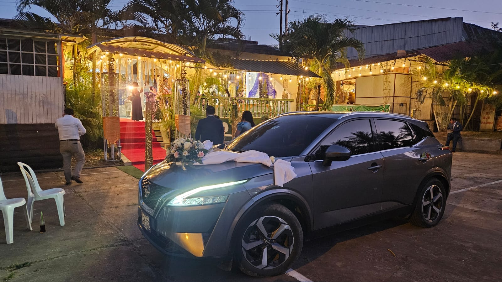 Auto nupcial decorado con flores frente al ingreso iluminado de El Bijao
