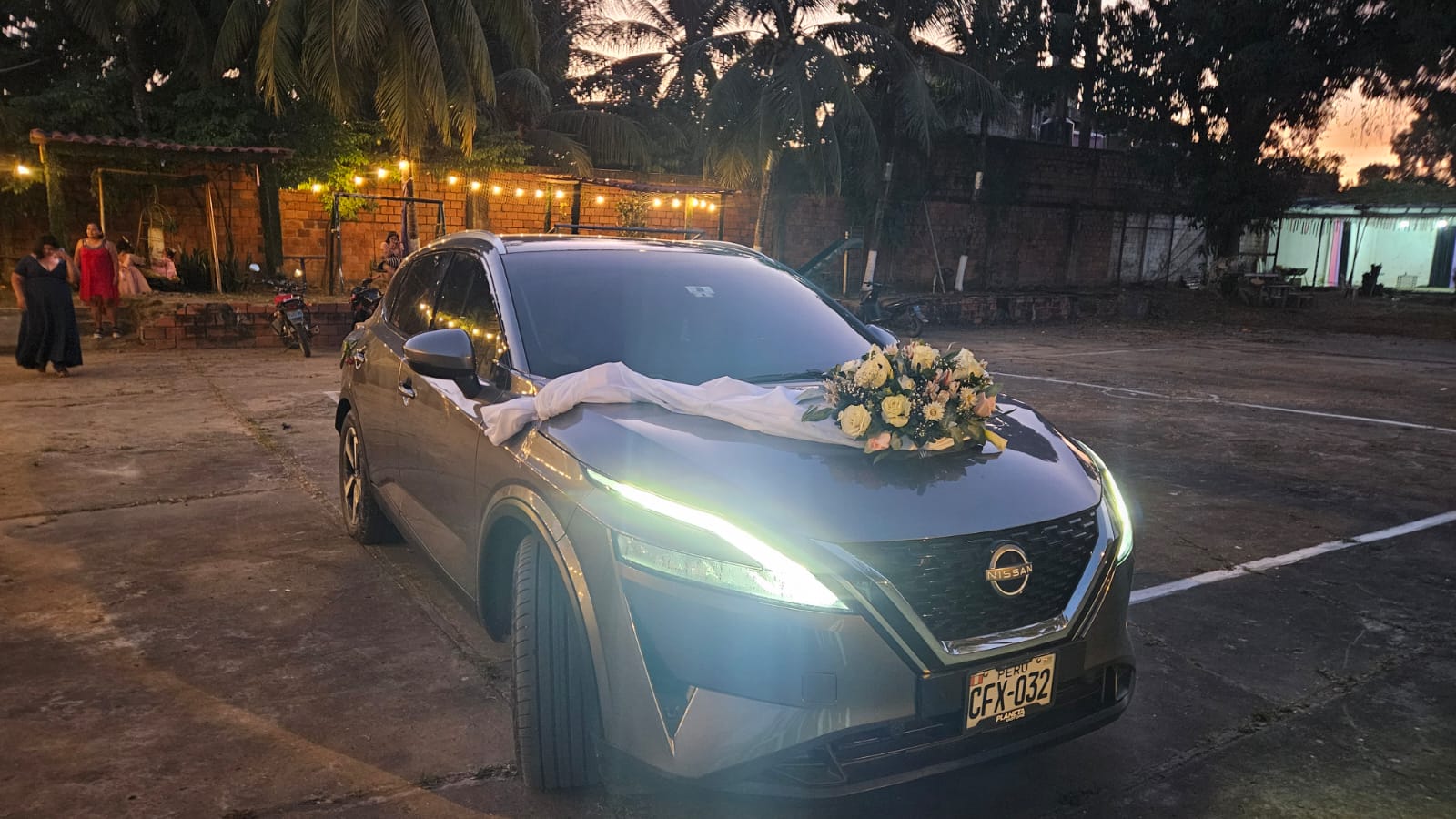 Auto de novios adornado con arreglo floral blanco en el patio de El Bijao