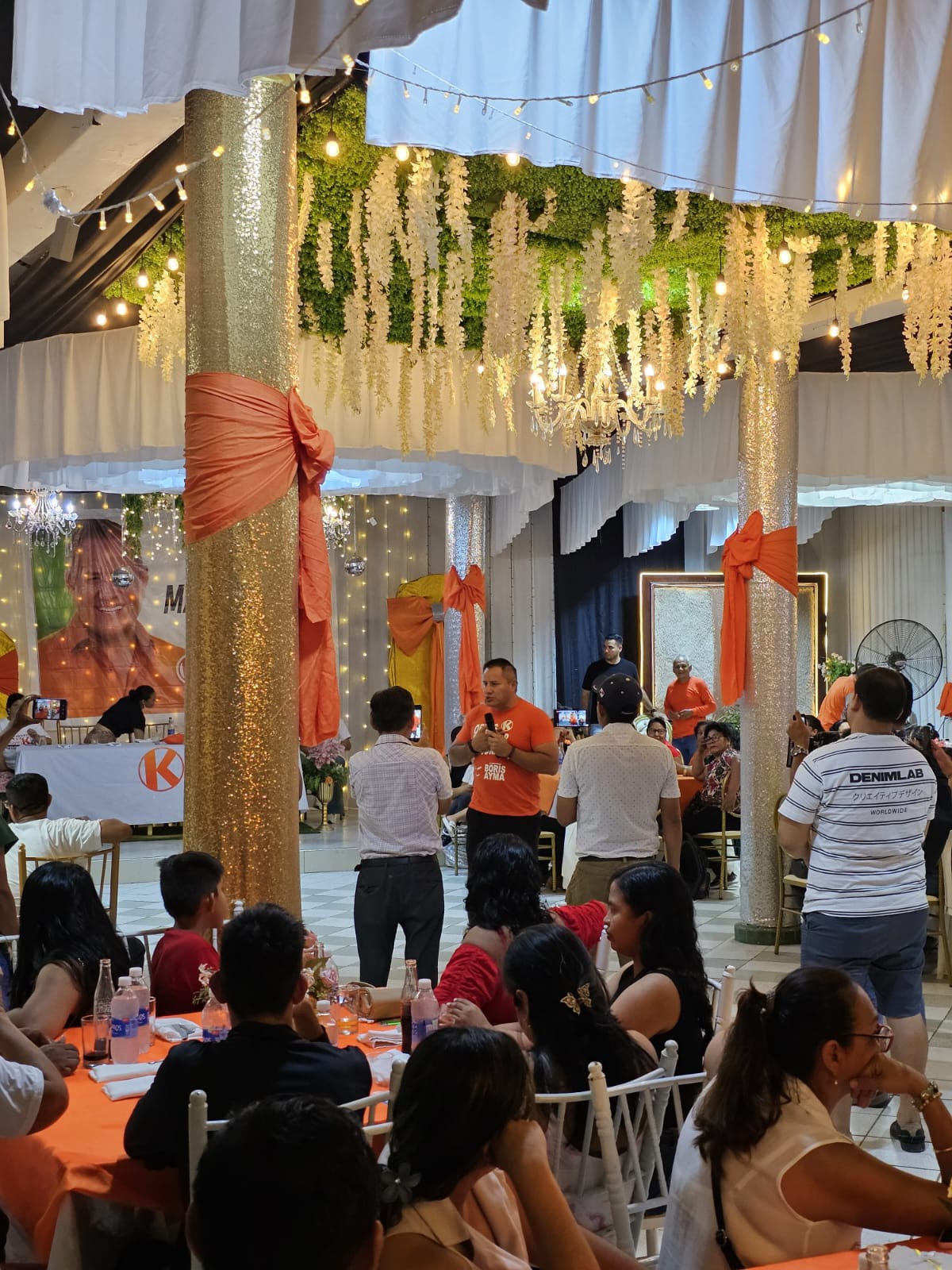Evento corporativo con decoración en tonos naranjas y mesas para invitados